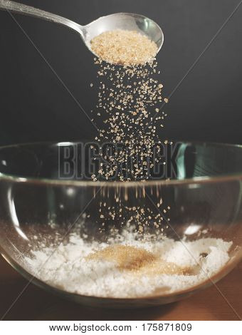 Close up Woman chief sprinkling sugar into glass bowl.