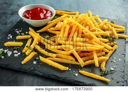 French fries with sea salt, cracked pepper and ketchup on stine board.