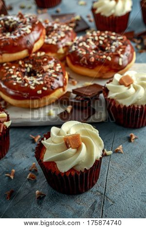 donut rings and vanilla caramel cupcakes with white and dark chocolate chippings and icing served on board.