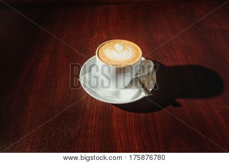 Cup of coffee to go on the wooden table with latte art. Street coffee. Top View. Color