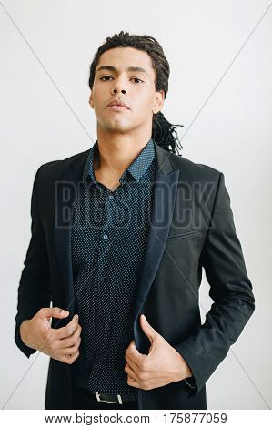 Happy young businessman in black suite and blue shirt standing over white background. Portrait of a handsome  boy. Color