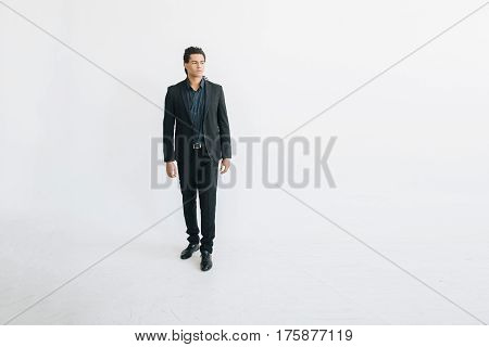 Happy young businessman in black suite and blue shirt standing over white background. Portrait of a handsome  boy. Color