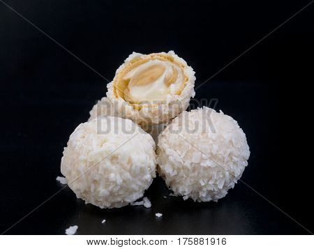 Raffaello white candy with coconut flakes on a black background