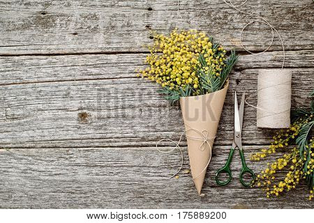 Make bouquet of mimosa. bandages twine and scissors on rustic wooden table. Copy space for text. top view