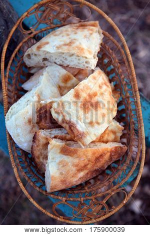 Fresh delicious Georgian bread in a woven openwork terracotta strawy plate, basket on a bright blue, azure background. Georgia, Caucasus