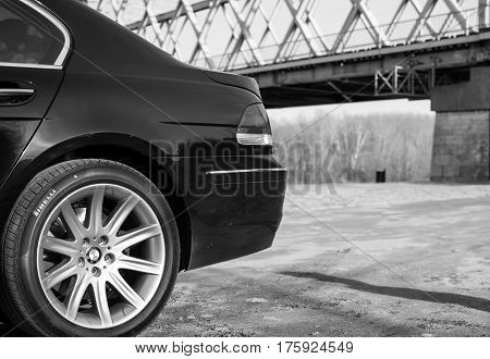 Senta, Serbia: March 4th, 2017. Close-up of beautiful black BMW 750Li car, photographed outdoor on a dock in Senta, besides beautiful big iron bridge.