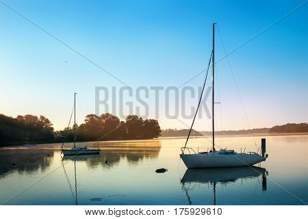Yachts float on the calm waters of the lake. Early morning. Masuria Poland .