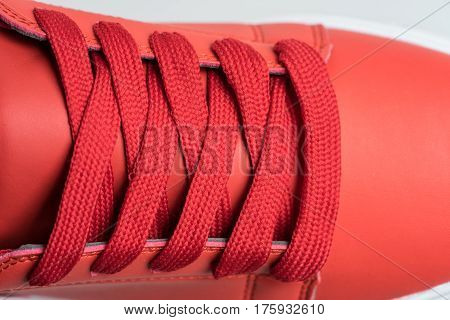 Fashion shoes with shoestring. Red sneaker and shoelace isolated on white background