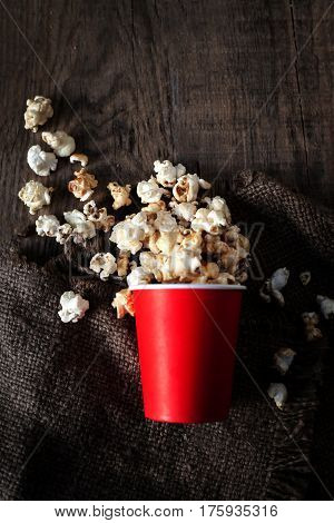Salt popcorn in a red cardboard box on the wooden table Cinema concept