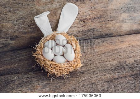 A Nest With Three White Easter Eggs And Bunny Ears At Home On Easter Day. Celebrating Easter At Spri