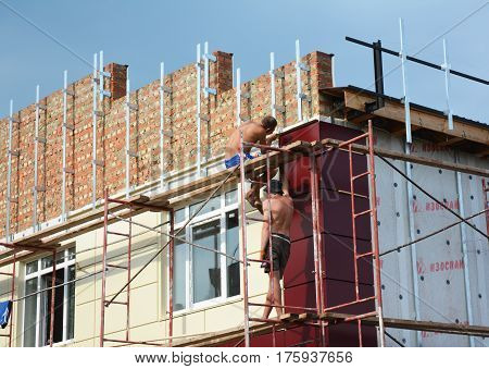 KIEV UKRAINE - March 14 2017: Construction workers insulating house facade with mineral rock wool. External wall insulation system (or EWIS) for energy saving.