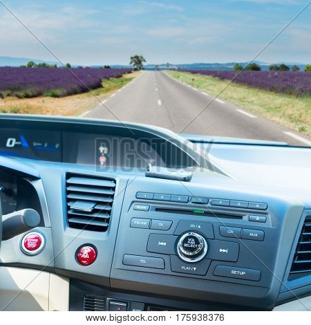 view of modern car dashboard with start power engine button and keys, summer road with lavender fields road in background