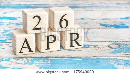 April 26th. Wooden cubes with date of 26 April on old blue wooden background.