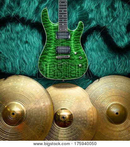 Green electric guitar with three cymbals on turquoise color faux fur wall. Musical instruments background