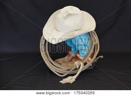 Western boots, hat and rope against a black background