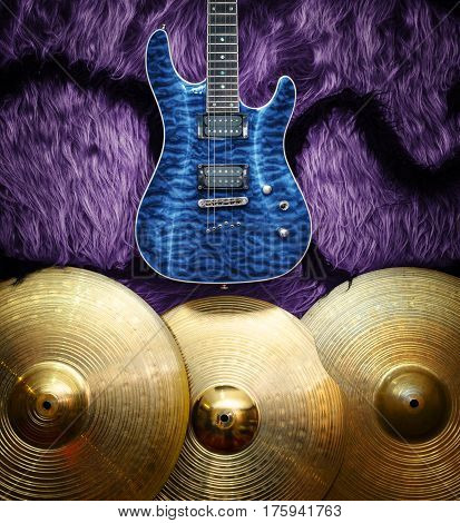 Blue electric guitar with three cymbals on faux fur wall. Musical instruments background