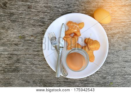 Fried Bread Stick Or Patongko And Soft-boiled Egg In White Dish With Fork And Knife On Wooden Backgr