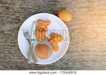 Fried Bread Stick Or Patongko And Soft-boiled Egg In White Dish With Fork And Knife On Wooden Backgr