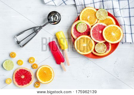homemade citrus popsicles with fresh fruit slices on stone table background top view