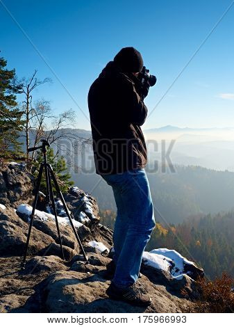 Man Takes Photos With Camera On Sharp Rock. Dreamy Fogy Landscape