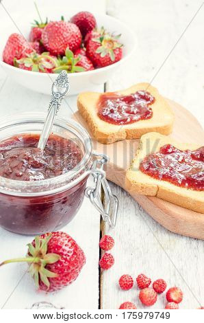 Toasts with strawberry jam for breakfast on white rusric wooden background. Selective focus.