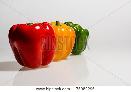 three different colored peppers in front of whites background