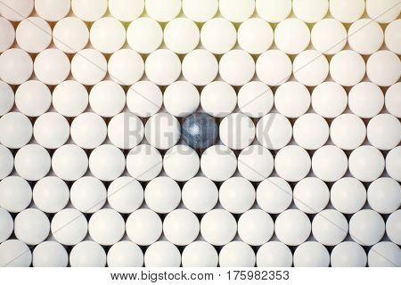 Black Bulb Among Many White Ones. Background Of Airsoft Balls