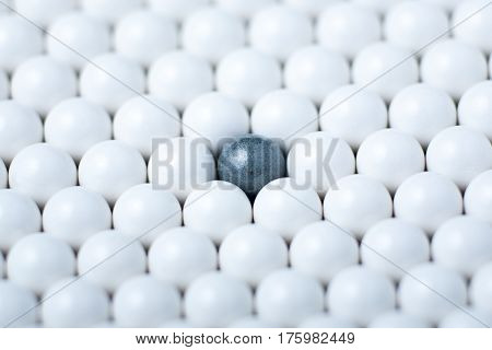Black Bulb Among Many White Ones. Background Of Airsoft Balls