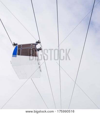 White and blue cable car against a cloudy sky