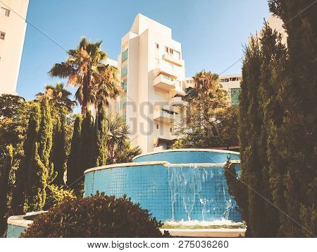 Residential Buildings And Fountain Surrounded With Green Plants In  Rishon Le Zion.