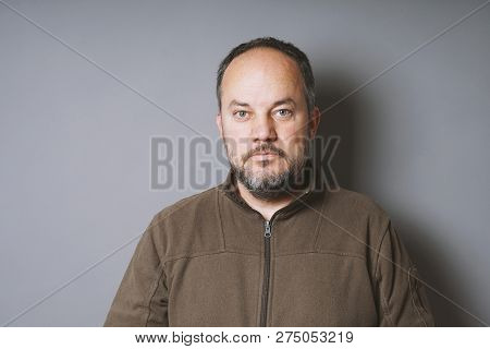 Middle Aged Man In His 40s With Short Dark Hair And Graying Beard Against Gray Wall With Copy Space