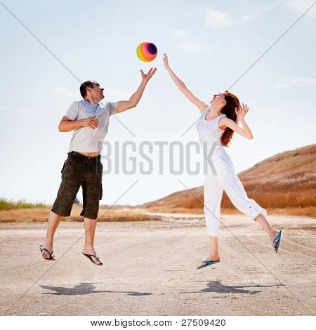 glÃ¼ckliches Paar springen, einen Ball zu fangen