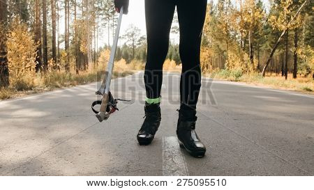 Training An Athlete On The Roller Skaters. Biathlon Ride On The Roller Skis With Ski Poles, In The H