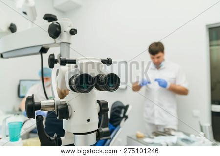 Doctor Used Microscope. Dentist Is Treating Patient In Modern Dental Office. Operation Is Carried Ou