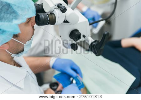 Doctor Used Microscope. Dentist Is Treating Patient In Modern Dental Office. Operation Is Carried Ou