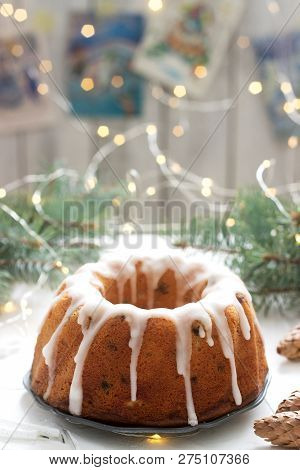 Pie With Raisins And Icing From Powdered Sugar On The Background Of Fir Branches And Garlands. Rusti