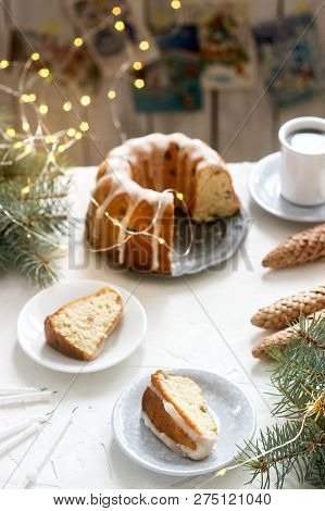 Pie With Raisins And Icing From Powdered Sugar On The Background Of Fir Branches And Garlands. Rusti