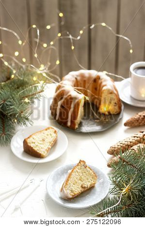 Pie With Raisins And Icing From Powdered Sugar On The Background Of Fir Branches And Garlands. Rusti