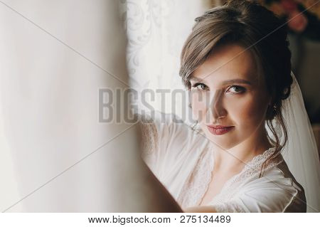 Beautiful Stylish Brunette Bride Posing In Silk Robe Near Wedding Gown In The Morning. Sensual Portr
