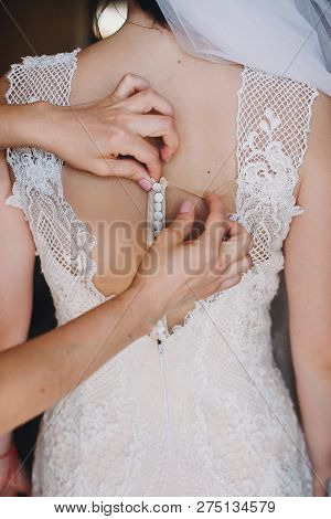 Bridesmaids Helping Bride Get Dressed In The Morning. Hands On Buttons On  Amazing Gown Of Gorgeous