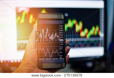 Businessman trading exchange board data on mobile screen / forex charts graph exchange on smart phone - Hand man and Stock market chart / Money forex Trade Graph Chart financial Concept