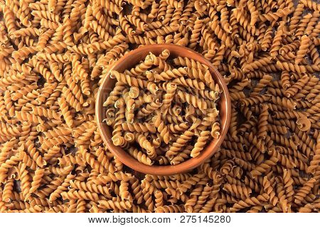 Top View Wholemeal Pasta. Integral Fusilli Into Bowl Over A Wooden Table