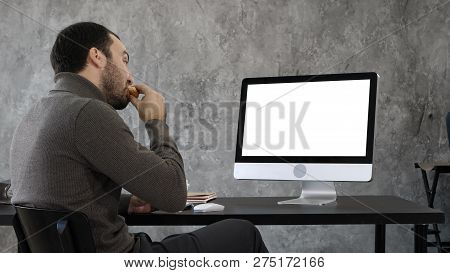 Handsome Businessman Eating And Having A Video Conference With Someone. White Display.