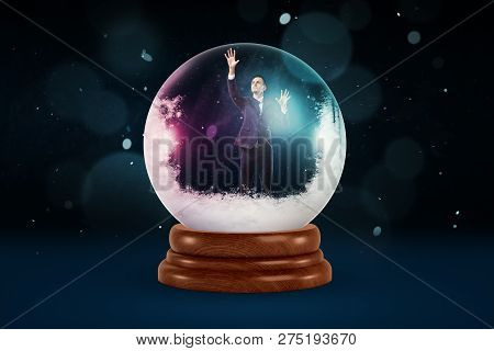A Tiny Businessman Inside A Snowy Crystal Ball On A Dark Background With Flecks Of Snow Falling.
