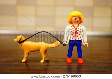 Poznan, Poland - December 22, 2018: Playmobil Toy Woman Walking Her Dog Out With A Line In Soft Focu
