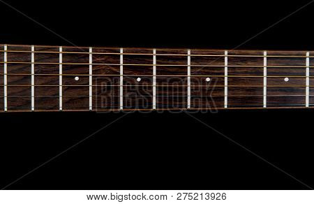 Acoustic Guitar Neck And Fretboard Isolated Against A Black Background