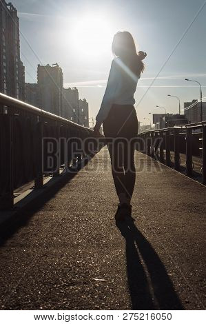Silhouette Of A Girl Against The Sun In The City