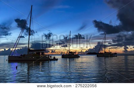 A Group Of Catamarans Sailed To The Island Of Bora Bora On The Sunset To Celebrate The New Year In T