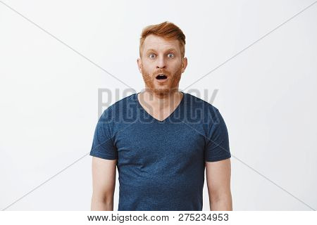 Redhead Male With Bristle Dropping Jaw As Seeing Incredible And Amazing Scenery, Posing Over Gray Ba