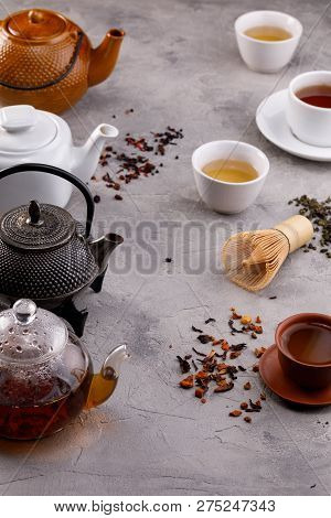 Tea Card. Variety Of Teapots And Cups On A Gray Background And Different Types Of Tea. Tea Still Lif